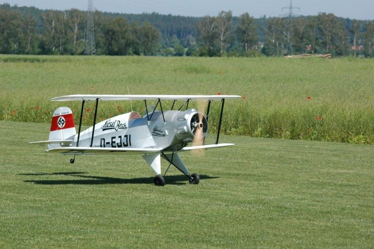 Eine historische Doppeldecker-Maschine auf einer Wiese beim Start.